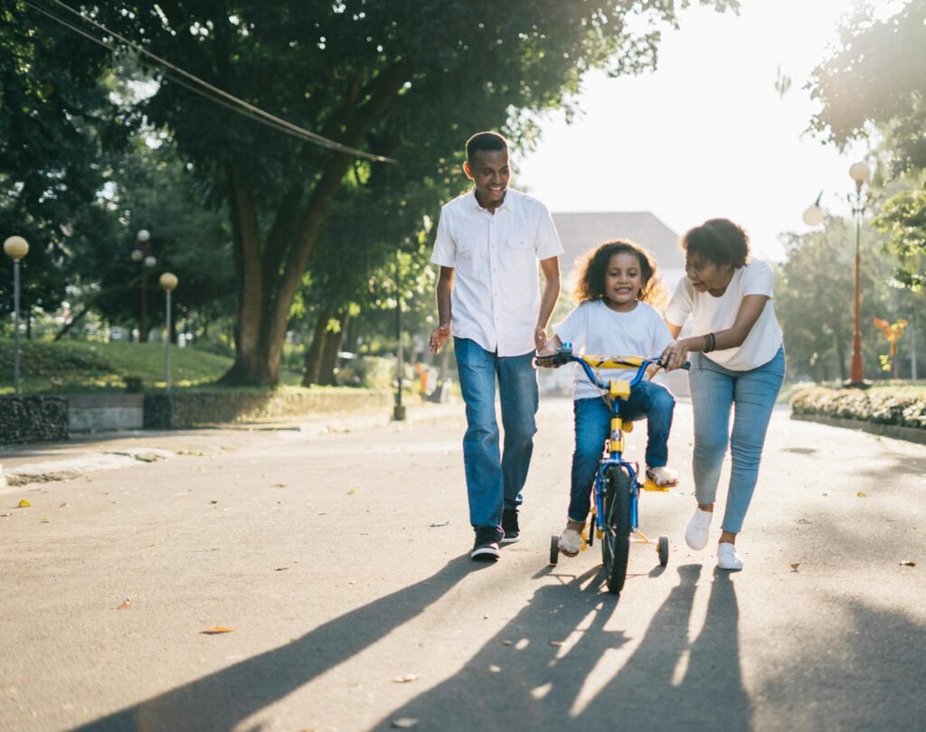 Man standing beside his wife teaching their child how to ride bicycle
