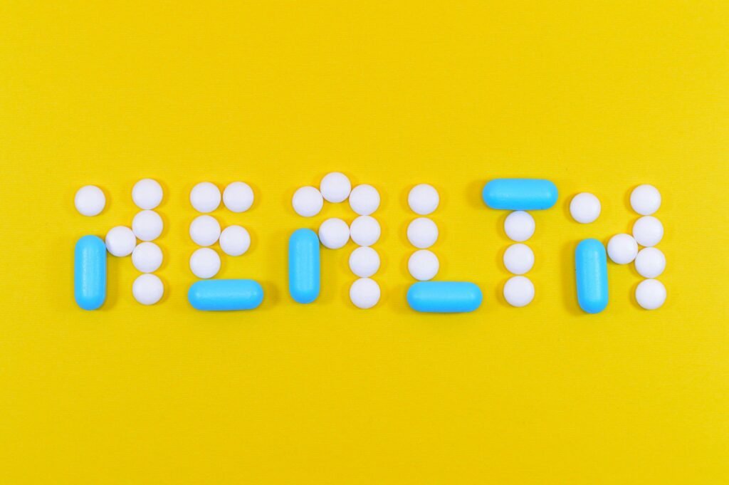 White and blue health pill and tablet letter cutout on yellow surface